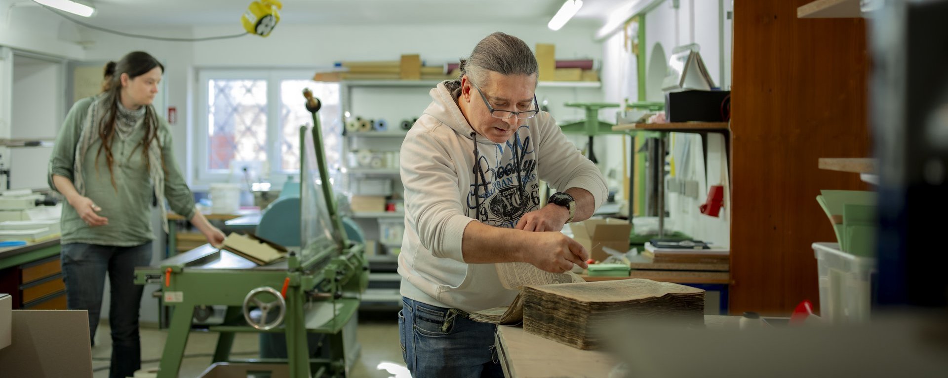 Ein Therapeut arbeitet mit einer Bewohnerin in der Werkstatt.